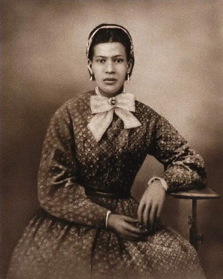 Photographie ancienne en sépia représentant Marie Laveau, prêtresse vaudou de la Nouvelle-Orléans au XIXe siècle, vêtue d’une robe à motifs et d’un large nœud, figure majeure de la sorcellerie créole