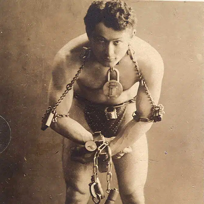 Harry Houdini en 1899, torse nu, enchaîné et menotté des poignets aux chevilles : le magicien né Erik Weisz à Budapest, futur roi de l’évasion