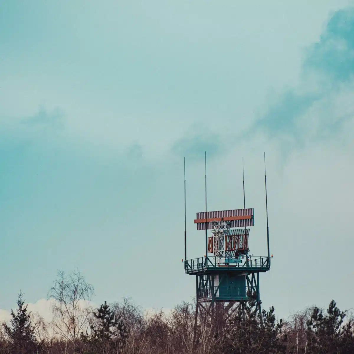Tour radar militaire au milieu d’une forêt, symbole des moyens de détection qui peinent à identifier les objets survolant les bases