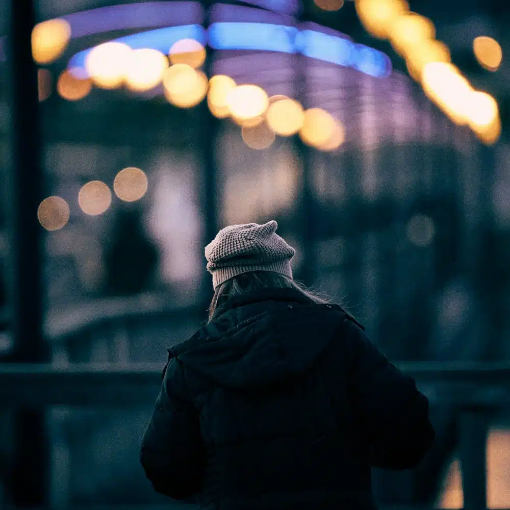 Personne marchant seule sous la pluie dans une rue de nuit : la femme libre mais seule, la solitude vendue comme une libération
